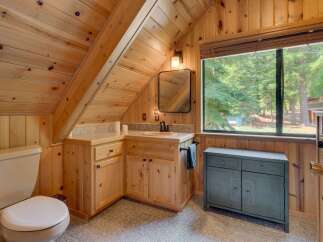 This charming bathroom features a rustic wooden interior with a sloped ceiling, creating a cozy cabin feel.