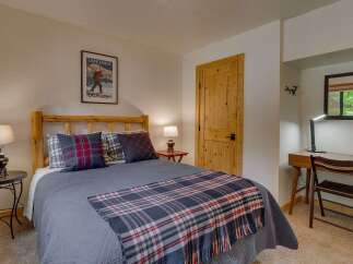 Discover this charming bedroom featuring a rustic log bed adorned with cozy plaid bedding and decorative pillows.