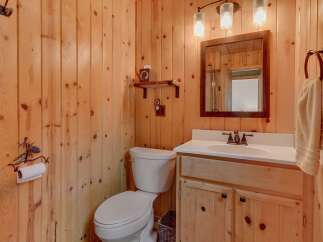 This rustic bathroom features warm wood-paneled walls, creating a cozy and inviting atmosphere.
