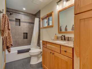 This modern bathroom features a sleek design with a tiled shower and bathtub, complemented by a stylish vanity with a granite countertop.
