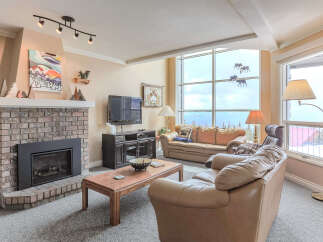 Experience breathtaking mountain views from this stunning living room, featuring a cozy brick fireplace and ample natural light.