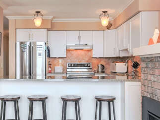 This modern kitchen features sleek stainless steel appliances, including a double-door refrigerator and a built-in oven.