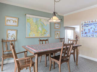 This dining room features a large wooden table adorned with a charming themed tablecloth, surrounded by classic wooden chairs.