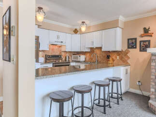 This kitchen features white cabinetry, granite countertops, and a tiled backsplash.