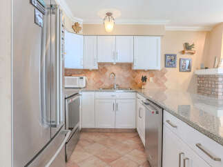 Discover this charming kitchen featuring sleek stainless steel appliances, including a refrigerator and dishwasher, complemented by elegant white cabinetry.
