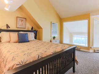 Discover comfort and style in this charming bedroom, featuring a plush queen-size bed adorned with a botanical-print comforter and accent pillows.