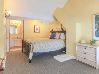 Discover comfort and style in this charming bedroom, featuring a cozy bed adorned with a blue and yellow floral duvet.