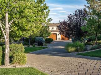 This stunning property features a beautifully paved driveway leading to a charming home with a classic architectural style.