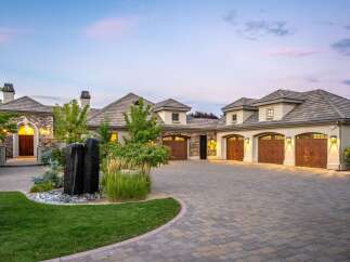 Experience luxury living in this stunning estate, featuring a grand stone entrance and a spacious multi-car garage.