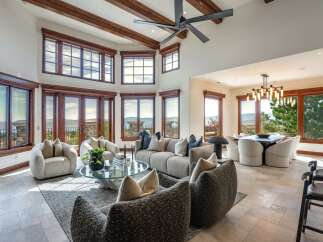 Experience breathtaking panoramic views from this stunning living space, featuring expansive windows and a grand fireplace.