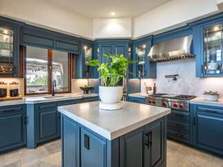 Experience luxury in this stunning kitchen featuring deep blue custom cabinetry and elegant marble countertops.