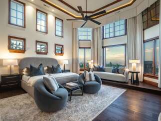 Experience luxury living in this stunning master suite, featuring a grand king-sized bed adorned with plush pillows and flanked by elegant bedside tables.