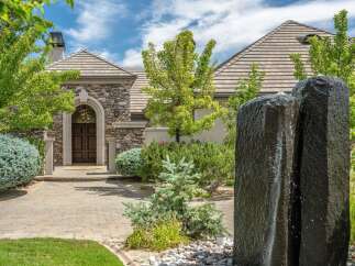 Experience luxury living with this stunning home featuring a grand stone facade and an elegant arched entryway.