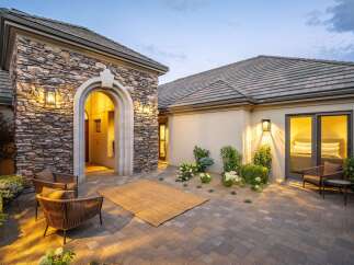 Experience luxurious outdoor living with this stunning courtyard featuring a charming stone archway and comfortable seating areas.