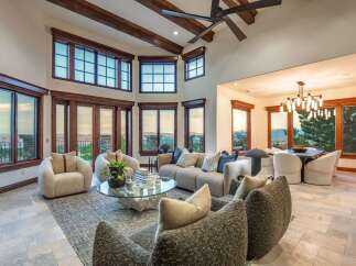 Experience breathtaking panoramic views from this stunning living room, featuring expansive windows and a soaring ceiling with exposed wooden beams.