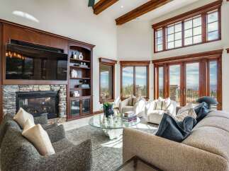 Experience breathtaking panoramic views from this stunning living room, featuring a grand stone fireplace and custom built-in cabinetry.
