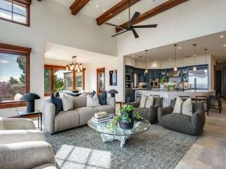 Experience luxurious open-concept living in this stunning home, featuring a spacious living area with vaulted ceilings and exposed beams, seamlessly flowing into a gourmet kitchen with custom cabinetry and a large island.