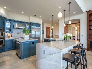Experience luxury in this stunning chef's kitchen, featuring custom navy blue cabinetry and sleek stainless steel appliances.