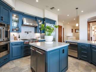 Experience luxury in this stunning chef's kitchen, featuring deep blue custom cabinetry and top-of-the-line Wolf appliances.