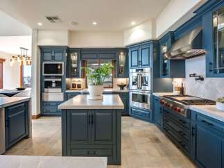 Experience luxury in this stunning chef's kitchen, featuring custom deep blue cabinetry and top-of-the-line stainless steel appliances.