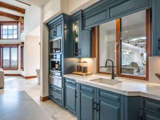 Experience luxury in this stunning kitchen featuring custom teal cabinetry and a built-in coffee maker.