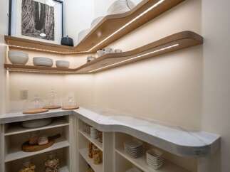 Discover this beautifully designed pantry, featuring custom-built, illuminated oak shelving that adds a warm glow to the space.