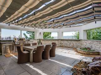Experience seamless indoor-outdoor living with this stunning covered patio, featuring a built-in grill station and a spacious dining area perfect for entertaining.