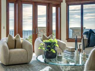 Experience breathtaking ocean views from this stunning living room, featuring plush armchairs and a modern glass coffee table.