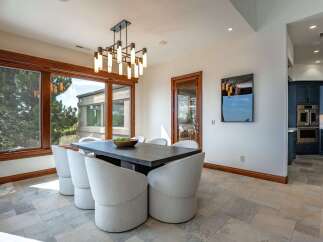 Experience elegant dining in this beautifully appointed space, featuring a striking modern chandelier and comfortable, upholstered chairs surrounding a dark wood table.