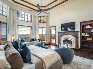 Experience luxury living in this stunning master suite, featuring a grand fireplace and expansive windows with breathtaking mountain views.