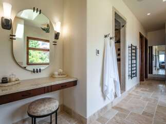 Experience luxury in this stunning bathroom featuring a spacious vanity with a large oval mirror and elegant sconce lighting.