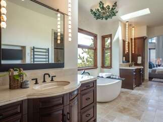 Indulge in luxury in this stunning master bathroom, featuring a freestanding soaking tub with a view of the surrounding trees.