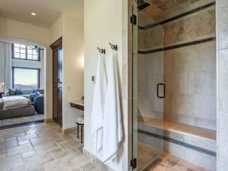 Experience luxury in this master bathroom featuring a spacious glass-enclosed shower with elegant tilework and a built-in bench.