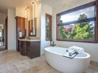 Indulge in luxury in this stunning master bathroom, featuring a freestanding soaking tub with a scenic view.