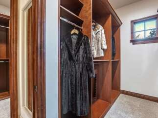 Step into this luxurious walk-in closet, featuring rich wooden built-ins and ample hanging space for your designer wardrobe.