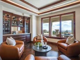 Experience luxury living in this stunning room featuring a custom built-in bar with glass-front cabinetry, perfect for entertaining.