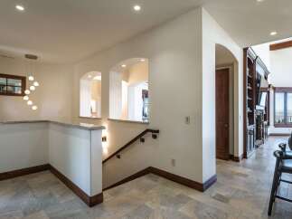 This spacious hallway features elegant arched openings and a modern chandelier, creating a sophisticated entryway.