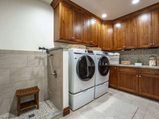 This spacious laundry room features a dedicated dog washing station with a shower and a wooden bench, perfect for pet owners.