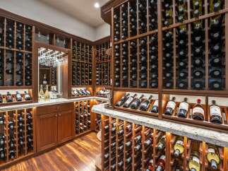 Indulge in the ultimate wine connoisseur's dream with this custom-built wine cellar, featuring extensive wooden racks for hundreds of bottles and elegant glass displays.