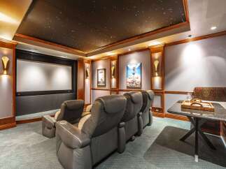 Experience cinematic bliss in this luxurious home theater, featuring plush reclining seats and a massive projector screen for an immersive viewing experience.