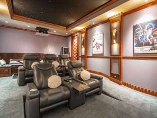 Experience ultimate cinematic comfort in this luxurious home theater, featuring plush reclining leather seats and a stunning starry night ceiling.
