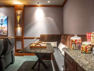 Experience ultimate entertainment in this home theater, featuring plush leather recliners and a cozy built-in banquette perfect for movie nights.