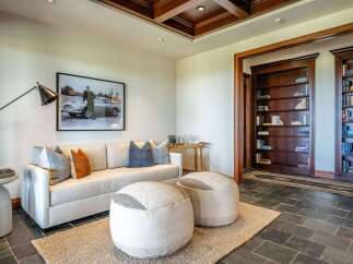Step into this sophisticated lounge area, featuring a plush sofa adorned with accent pillows and two stylish ottomans perfect for relaxation.