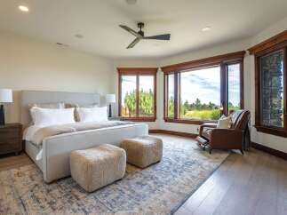Experience luxury living in this stunning master bedroom, featuring a plush king-sized bed, comfortable seating, and a modern ceiling fan.