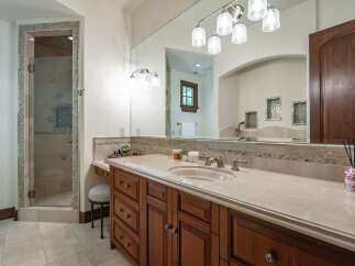 Indulge in luxury with this stunning bathroom featuring a spacious glass-enclosed shower and a beautiful wooden vanity with a marble countertop.
