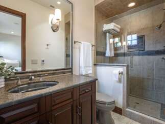 This luxurious bathroom features a spacious vanity with a granite countertop and a deep undermount sink, complemented by rich dark wood cabinetry.