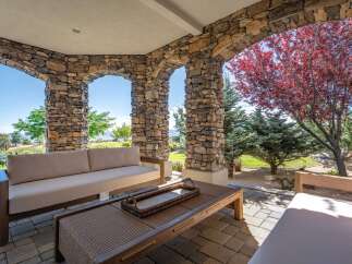 Enjoy outdoor living at its finest on this covered patio, featuring a comfortable sectional sofa and a stylish coffee table.