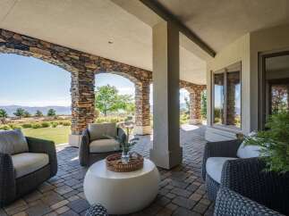 Enjoy breathtaking views from this covered patio, featuring a charming stone archway and comfortable outdoor seating.