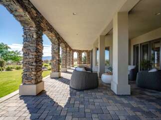 Experience luxurious outdoor living with this stunning covered patio, featuring elegant stone arches and a paved walkway.