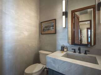 This modern powder room features a striking Venetian plaster wall, creating a sophisticated and textured backdrop.
